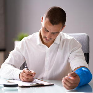 An injured professional sits at a desk with his arm in a cast - Cardinal Law Partners