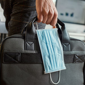 Professional man in suit holding a bag and mask in hand - Cardinal Law Partners